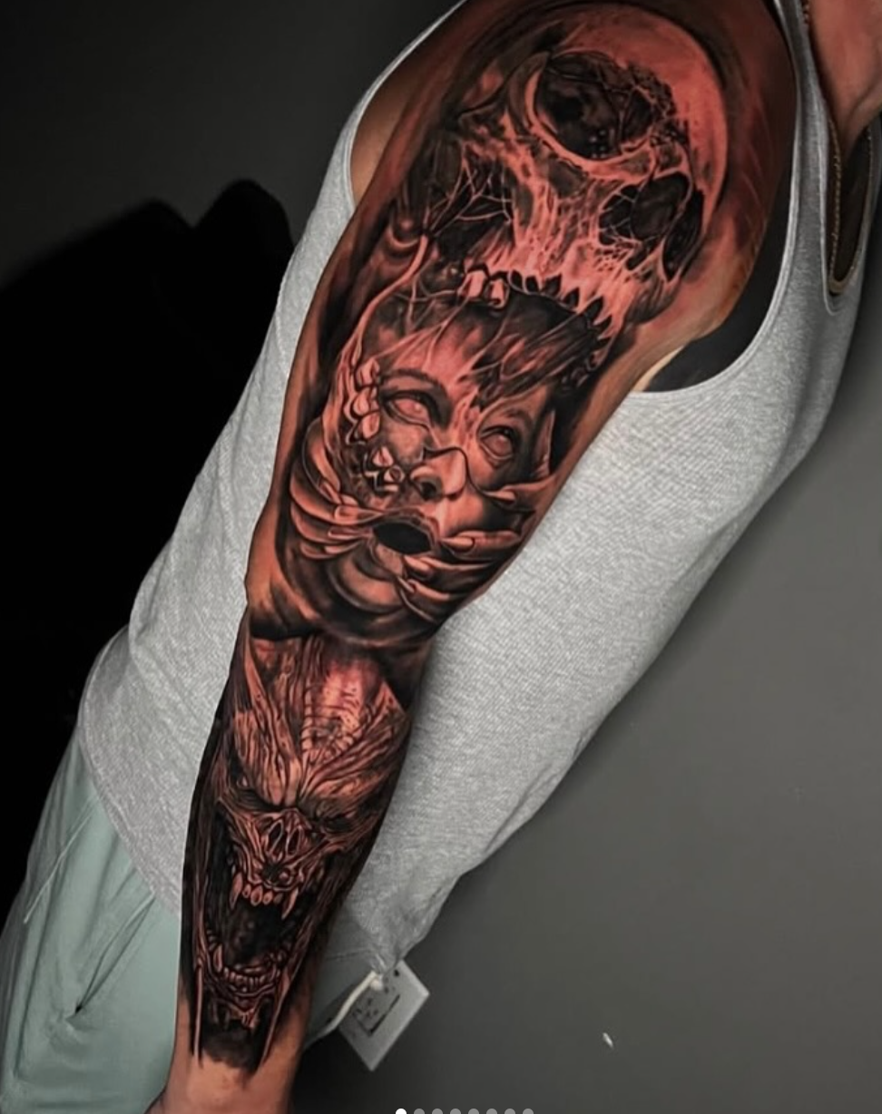 Dark full sleeve tattoo featuring skulls and a sinister portrait