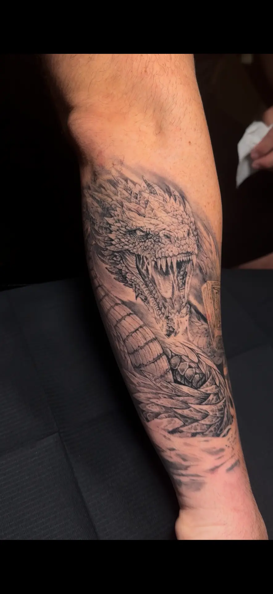 Black-and-grey roaring dragon forearm tattoo