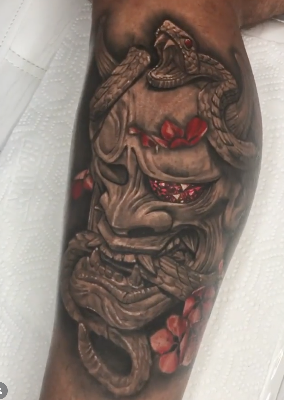 Black-and-grey Hannya mask and snake tattoo with red floral accents